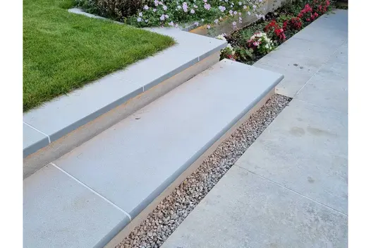 Contemporary Grey sandstone bullnose step rises past planted bed on 2 levels to coping edge of lawn from matching paving below.
