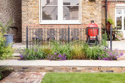 Natural stone steps with Cotswold Belgian brick risers descend to matching clay paver path from patio with railings and planting.