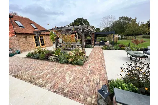 Cotswold Clay Pavers used in large garden with metal, and wooden pergolas, an outhouse and large lawn area..