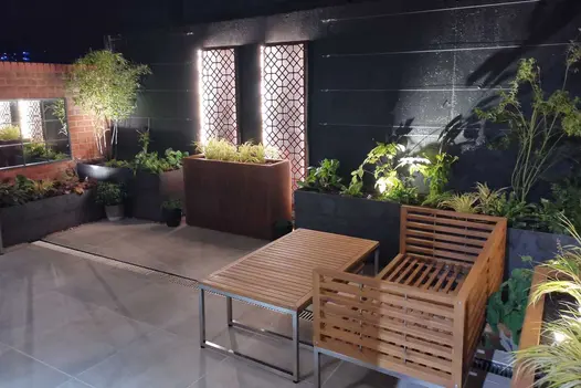 Courtyard at night, with Cream porcelain garden paving and channel drain, backlit screens and mirror. Design by Holland Landscapes.