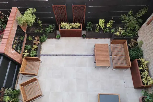 Overhead view of Cream porcelain paved courtyard. Trough planters sit against wall and fence. Built by Holland Landscapes.