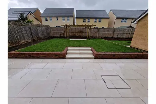 A minimalist design showing Florence Beige patio with steps leading to raised lawn area adorned with a pergola, offering a tranquil retreat in the backyard.