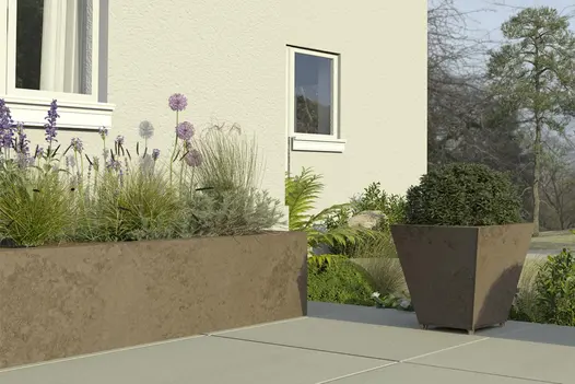 Cream rendered house wall with large tapered planter and raised bed faced in Dark Mocha exterior cladding. Lawn and trees beyond.
