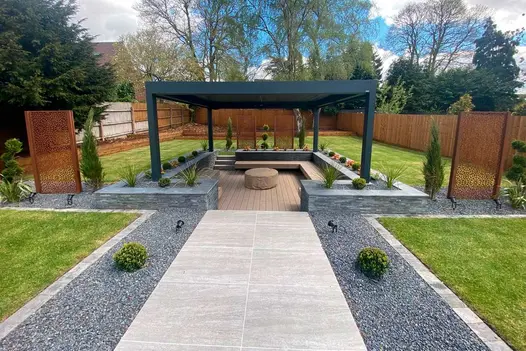 Path leads to sunken firepit area with pergola and raised flowerbeds turned built-in bench sits on traditional designboard composite decking.