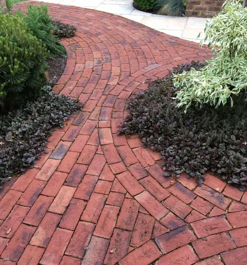 Flowerbeds enclosed by circles of romsey antique clay pavers show off black and red tones next to mint coloured sandstone.