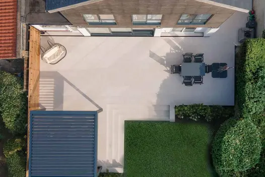Aerial view of spacious garden patio laid in Egyptian Light Porcelain paving, with steps and dining area.