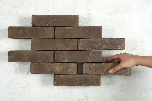 Hand places a Verona Clay Paver into formation of nine other bricks arranged in rows of 1 and 2. Free UK delivery available.