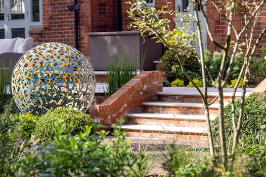 Large circular metal structure at the end of set of Egyptian Beige Limestone Bullnose steps. Mowtivated see garden step ideas come to life.