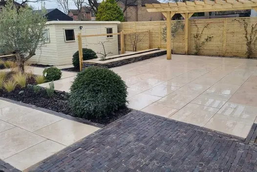 Mixed paving of Egyptian beige limestone and grey clay pavers with wooden pergola, narrow rectangular beds and a garden room.