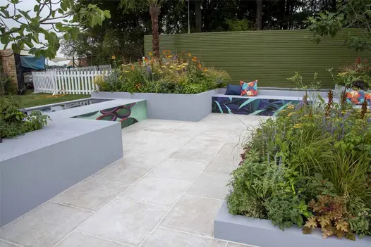 Egyptian Beige Limestone paving with rectilinear grey raised beds, green slatted fence and low leafy planting by Emma Tipping.