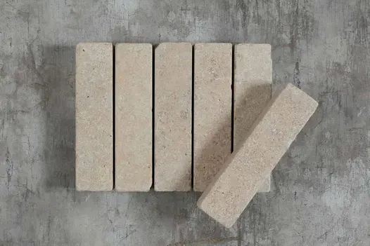 5 Egyptian Beige limestone patio bricks against a grey background, showing markings, with 6th balanced at an angle on top.