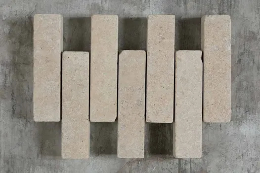 7 Egyptian Beige stone pavers on grey background, showing colour and tumbled edges. Free UK delivery available.