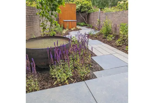 Large water bowl in bed passed by path of Midnight Black limestone paving and granite planks arranged with a geometrical outline.