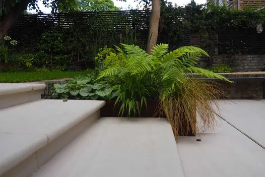Faro Porcelain 40mm Bullnose Steps crafted by our stone masons in the Bespoke Stone Centre, with mature planting on the side.