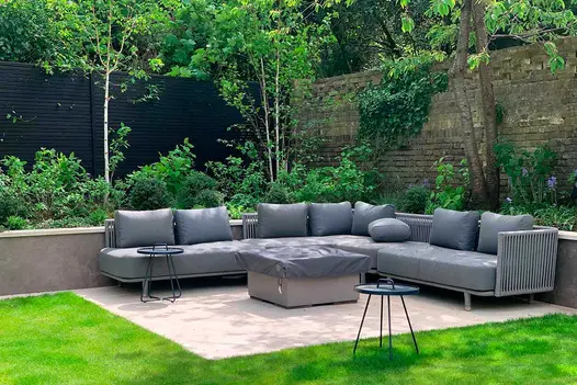 Large modular rattan furniture garden set in a green, outdoor area paved with Faro vitrified tiles supplied by London Stone.