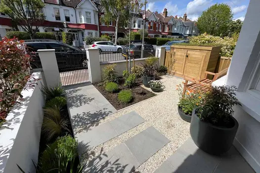 Front garden adorned with light coloured pebbles has Flamed Grey Sawn Sandstone paving slabs used as stepping stones towards front of house.