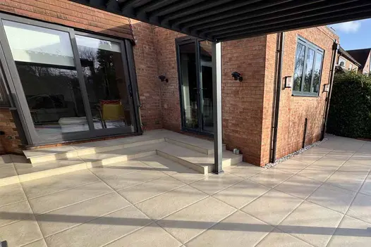 Wide view of outdoor steps built using Florence Beige 20mm Bullnose Step, leading to patio doors with classical planters.