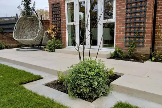 Florence Beige paving across back of house, with step up to french doors and step down to lawn with matching owing strip. 