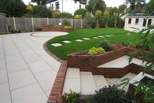 Brick-edged Florence Beige porcelain patio by Manor Landscapes. Benches topped with matching paving slabs in sunken seating area.