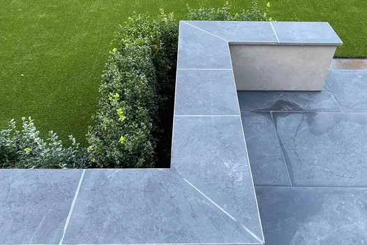 Low white wall with Florence dark coping between matching patio and box hedge, seen from above. Built by The Greatest Scapes.