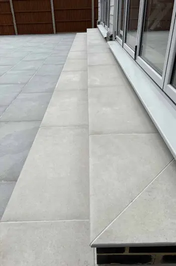 Side view of set of florence grey 20mm moulded bullnose steps next to white french doors, leading to patio.