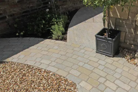 Flowpoint Natural Grey jointing mortar between tumbled limestone setts and linear paving in a curved garden pathway.