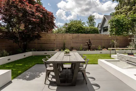 Patio dining area with a lawn and surrounding white rendered retaining walls with Sidewalk porcelain patio.