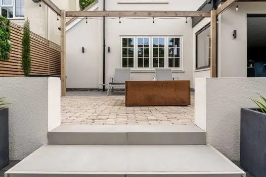Set of Yard porcelain steps looking up towards a cobbled courtyard garden and white rendered house.