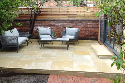 Grey garden furniture sits on harvest sawn sandstone with one bullnose step leading up to garden building.