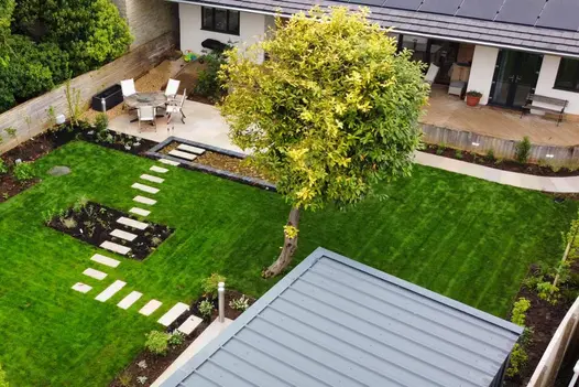 View from above shows large lawn area with stepping stones over flowerbeds and pond, leading to raj green porcelain patio.