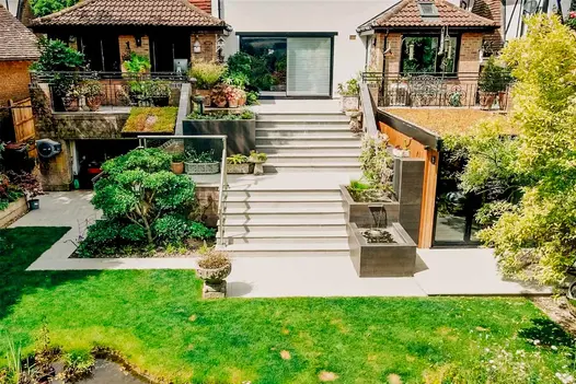 Huge outdoor kandla grey porcelain staircase has cladding used on water feature leading down the bullnose steps.