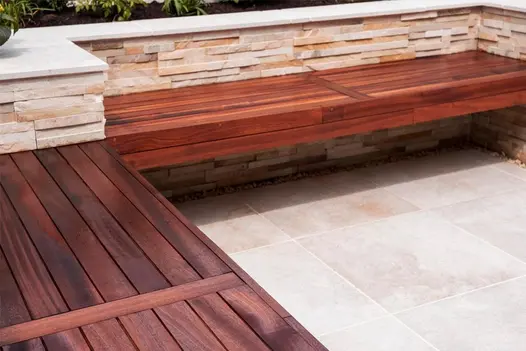 Close image of seating area made out of cedar benches, stone cladding on walls and Gea Porcelain patio tiles on the floor.