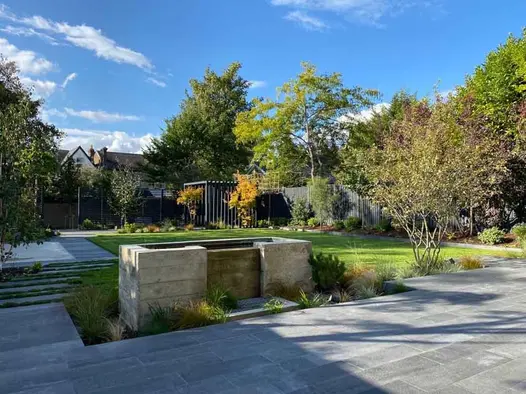 Black Granite plank paving and white pebble path runs past wooden deck with suspended egg chair. Design by Gardens of the Future.