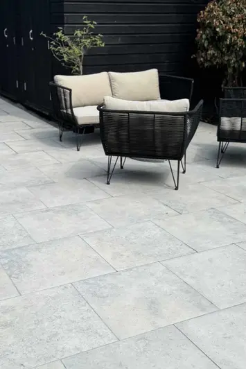 Portrait view of jura grey porcelain paving with rattan outdoor furniture in the background shows off unique markings.