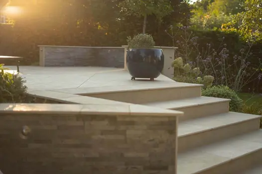Acutely angled corner of raised bed, topped with Golden Stone Porcelain bullnosed coping stones shaped to fit.