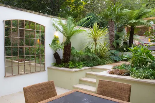 Golden Stone flat coping stones top white-rendered retaining walls in garden that rises from patio of matching paving.