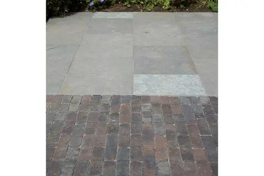 Near view of Graphite grey limestone slabs laid next to clay pavers in garden design by Bramley Apple, built by Waterfeatures Ltd.