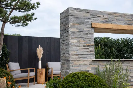 Rectangular block of Graphite Sandstone Cladding, with cut-out framing hedge beyond, in show garden at RHS Malvern Flower Show.