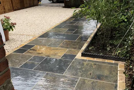 Wet Rustic Slate Paving in project packs shows off natural texture in neat path with shingled area to the left.