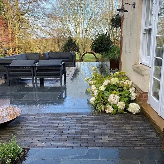 Silver Grey Multi clay paver strip leads between paving from french doors to bowl water feature on raised patio with lounge set.