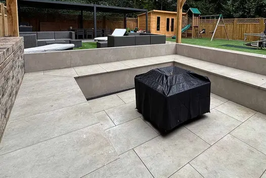 Relaxed lounge area using Grey York Porcelain Paving with adjacent artificial lawn and modern garden furniture.
