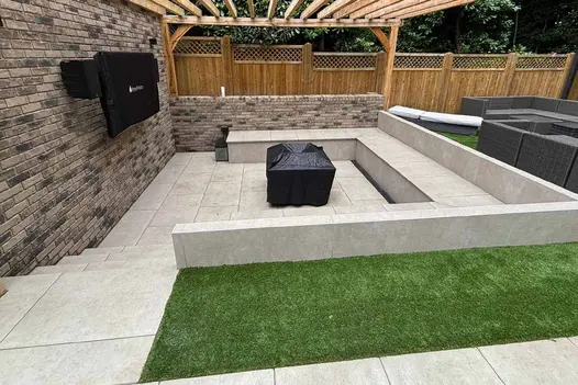 Sunken outdoor seating area fully paved in Grey York Porcelain, with built-in benches and a central firepit.