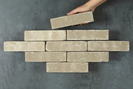 Hand puts single Gromo Antica Clay Paver onto top of formation of 8 other bricks arranged in rows. Free UK delivery available.
