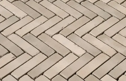 Section of Gromo Antica brick pavers laid herringbone pattern with wide, unsanded joints, showing tumbled edges and tonal variation.