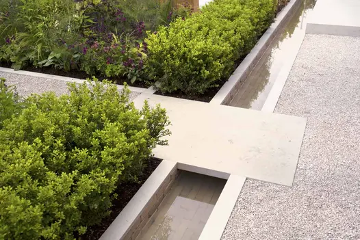 Gromo Antica clay pavers form a water feature running underwater with light coloured stepping-stone as bridge.