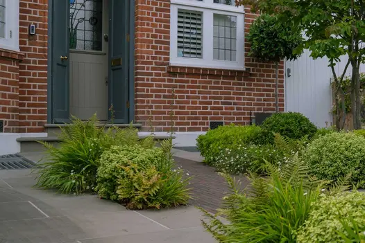 Brick path between planting approaches 2 Heath sawn sandstone bullnose steps to grey front door. Design by Harrington Bros.