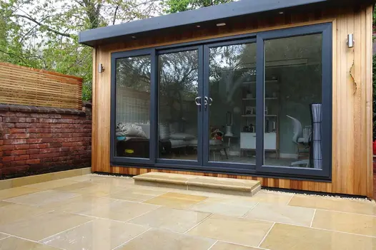 Wet Harvest Sawn Sandstone bullnose steps lead from garden building to matching patio with white grout.