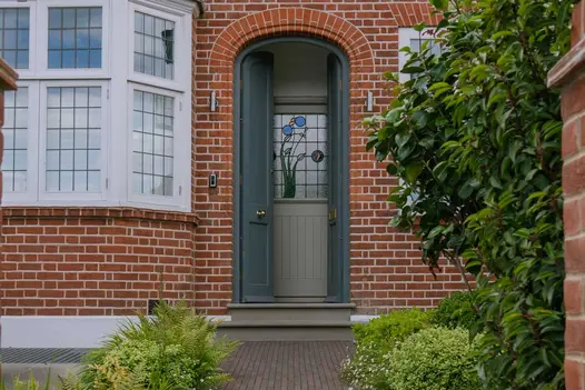 2 Heath smooth sandstone bullnose steps rise from clay paver path to grey front door of period house in design by Harrington Bros.