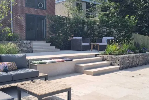 7 Egyptian Beige Limestone steps with patio host to furniture inbetween, leads up to black french doors, away from larger patio.