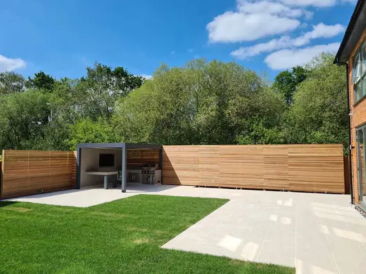 Outdoor cooking area located under Deponti metal pergola, paved with Faro Porcelain Paving supplied by London Stone.